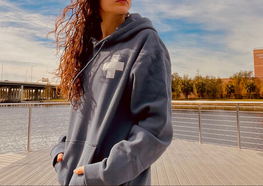 Girl wearing a blue hoodie with a cross on it looking over her shoulder.